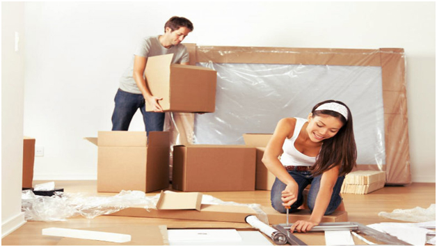 A man keeping boxes together and a women dismantling a table