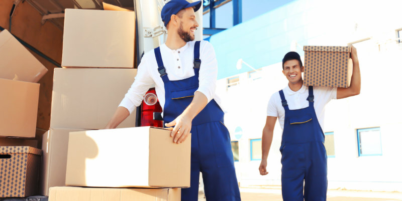 two men in uniform lifting corrugated boxes