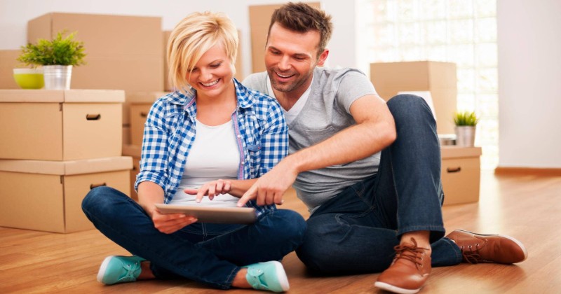 a man and a woman holding laptop searching house options online