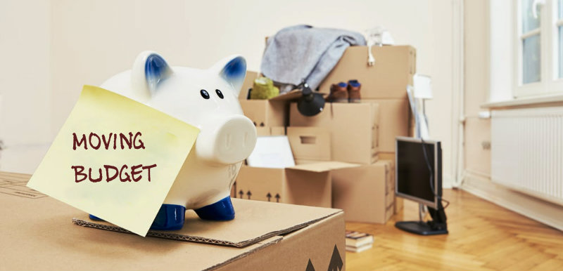 Piggy bank kept on the packed boxes with moving budget slip on it
