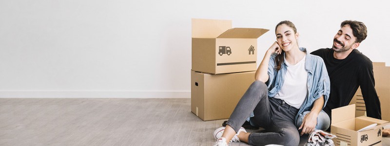 happy couple sitting on the floor with their cardboard boxes