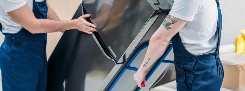 cropped picture of professionals trying to move a refrigerator