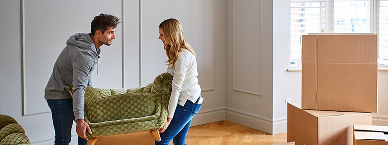 young couple trying to lift heavy furniture