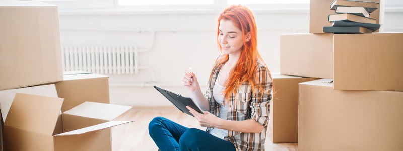 young woman sitting on the floor and planning for household relocation