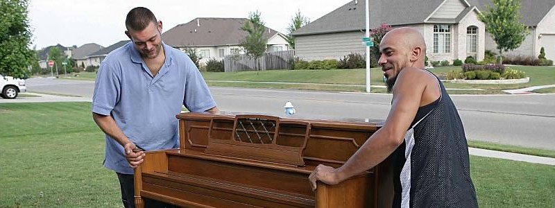 two men carrying piano