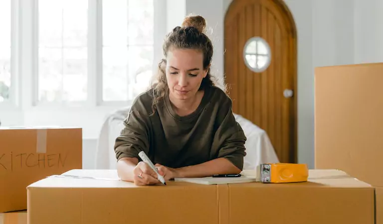 woman writing something on a cardboard box