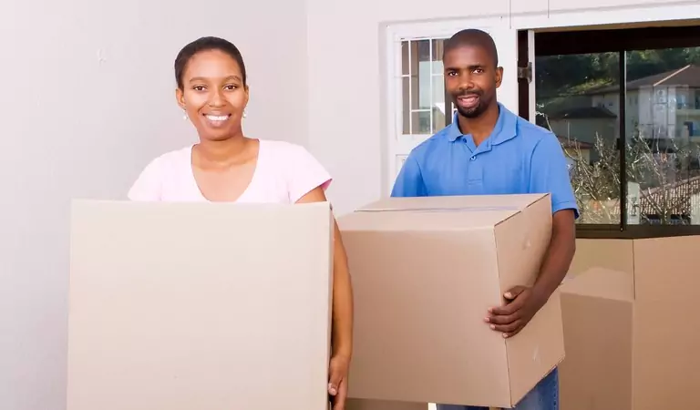 couple holding heavy boxes inside of a house
