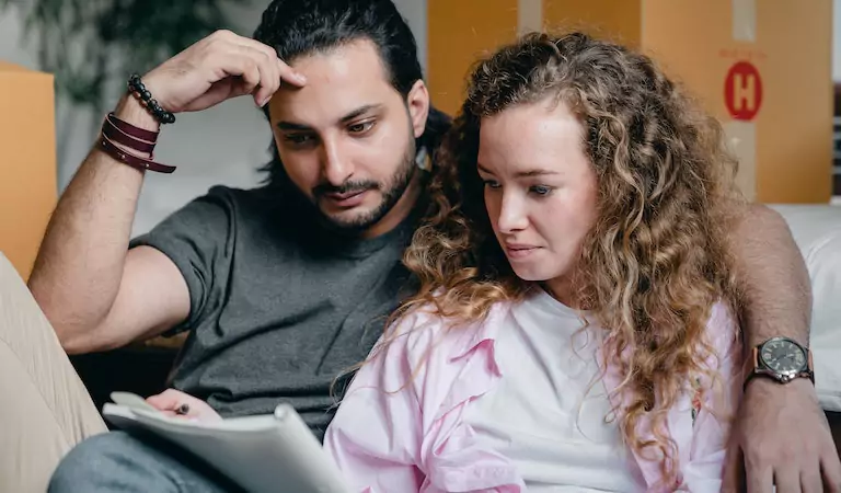 couple sitting inside of a house and calculating something