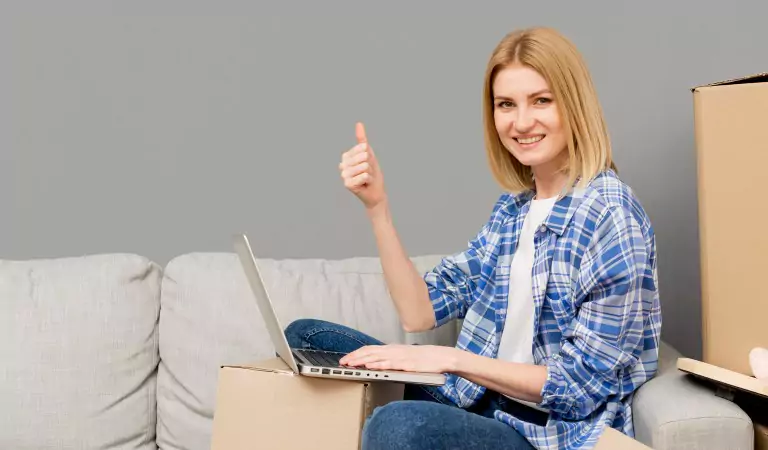 young woman showing thumbs up and working on a computer