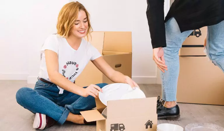 woman packing up plates into a box