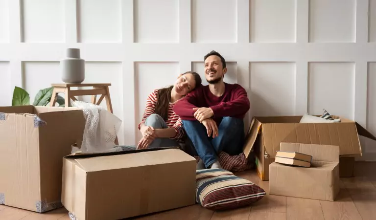 couple sitting with their household packed into the boxes