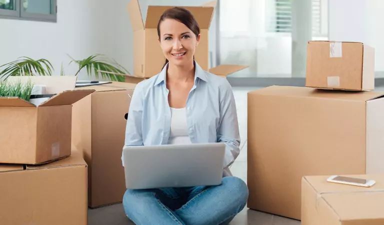 woman sitting on the floor with a computer and some boxes at the back