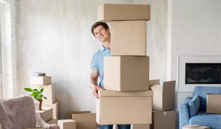 young man holding heavy cardboard boxes