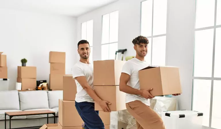 two young man with cardboard boxes inside of a new house