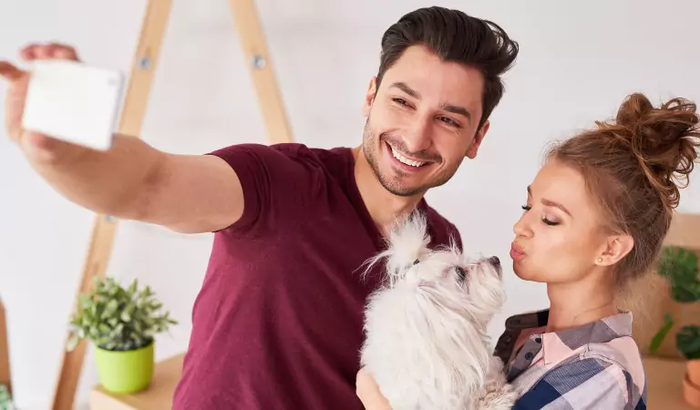 couple looking happy with their pet inside of a new house