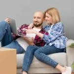 couple sitting on a couch and watching something on a laptop