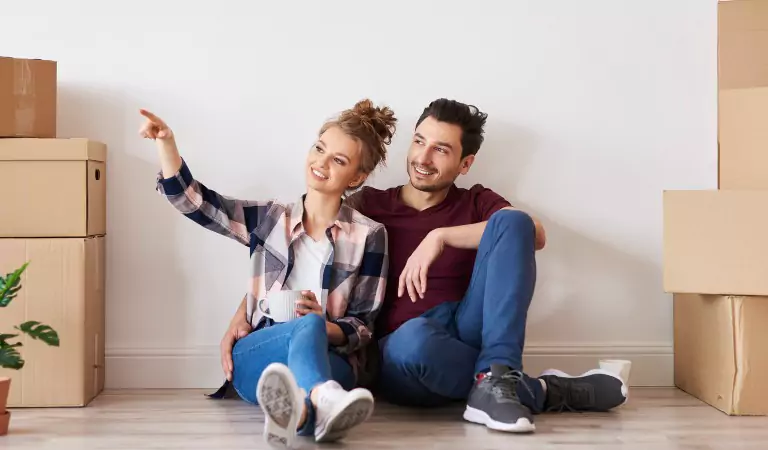couple with some cardboard boxes inside of their house