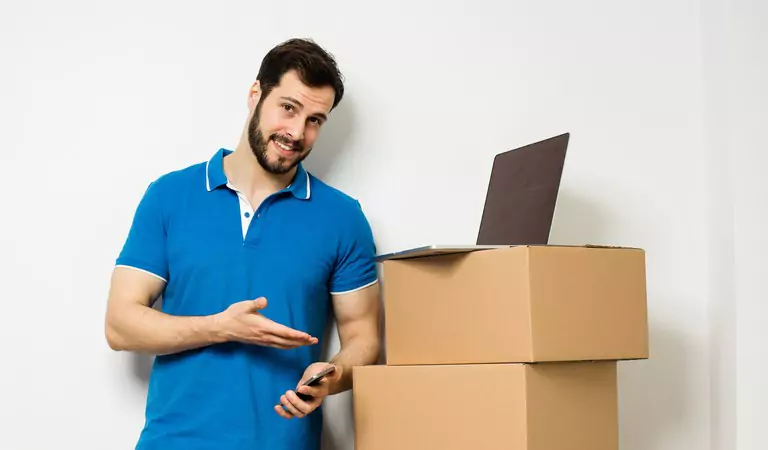young man with some cardboard boxes and a laptop on top
